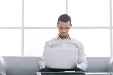 Otel lobisinde bir dizüstü bilgisayar kullanarak, işadamı çalışır.