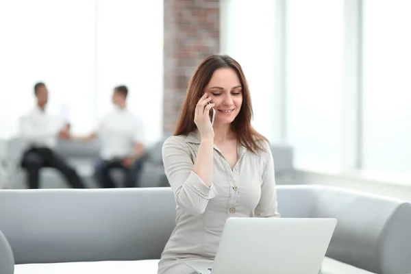 Giovane donna d'affari comunica con i suoi partner utilizzando laptop e smartphone — Foto Stock