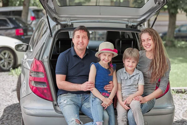 happy family sitting in the trunk of a family car