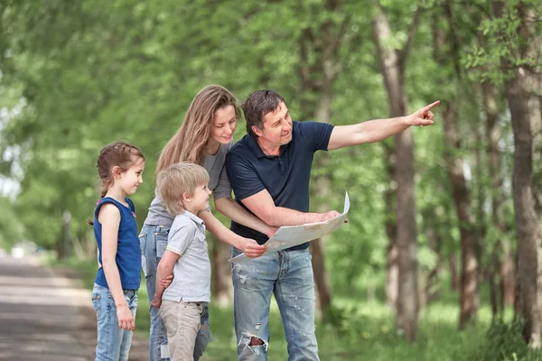 Familia con niños discutiendo la ruta de viaje en el mapa —  Fotos de Stock