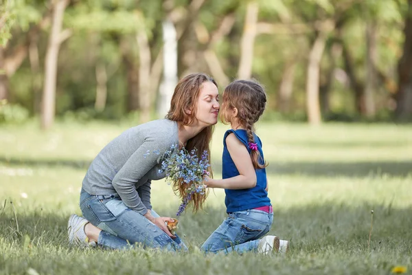 Счастливая мама и маленькая дочь, сидящие на лавке в парке . — стоковое фото