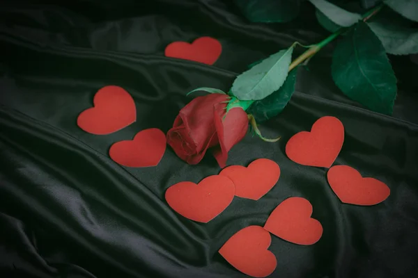 Rote Rose und Herzen auf schwarzem Seidenhintergrund — Stockfoto
