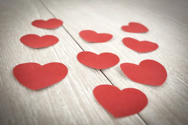 Corazones de papel rojo sobre fondo de madera claro. — Foto de Stock