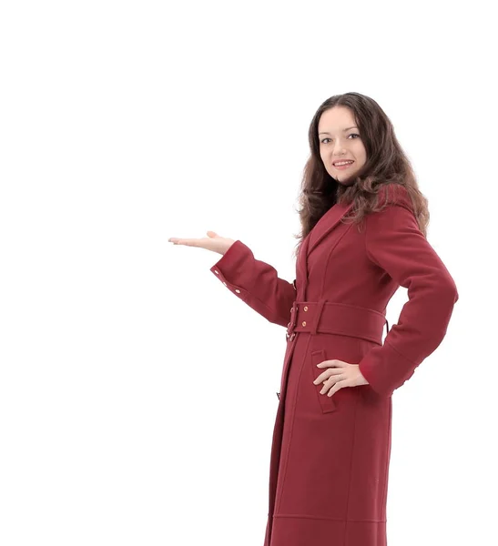 Усміхнена молода жінка в червоному пальто показує на копіювальному просторі — стокове фото
