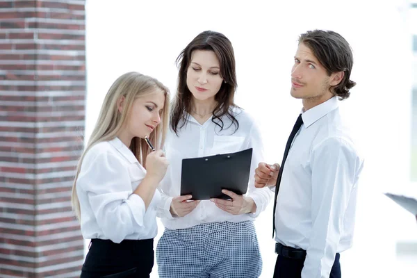 Collega's kijken naar zakelijke documenten permanent in het kantoor. — Stockfoto