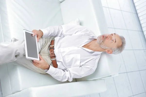 Ανώτερος επιχειρηματίας κοιτάζοντας ψηφιακή οθόνη tablet κάθεται στον καναπέ — Φωτογραφία Αρχείου