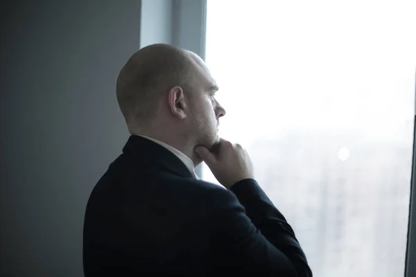 De cerca. pensativo hombre de negocios mirando por la ventana de la oficina —  Fotos de Stock