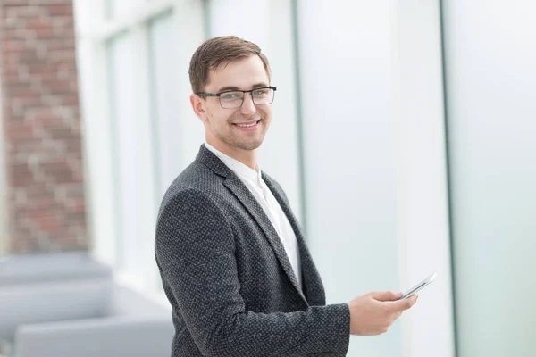 Бизнесмен со смартфоном стоит в светлом офисе — стоковое фото