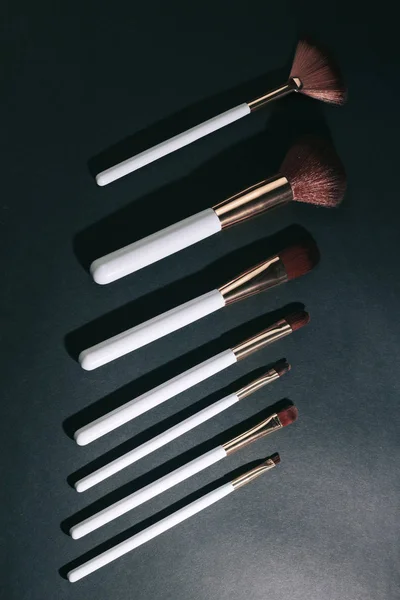 variety of makeup brushes on a black background.