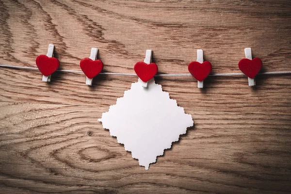 Hearts and blank note on the clothespin on wooden background. — Stock Photo, Image