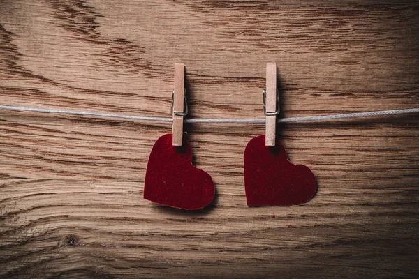 two red hearts on clothespins on wooden background