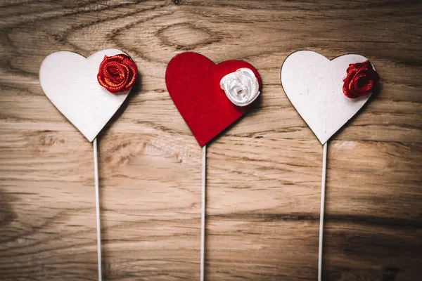 Red and white hearts with sticks on wooden table background. — Stock Photo, Image