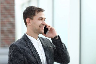 Onun akıllı ofis pencere yakınındaki konuşan işadamı.