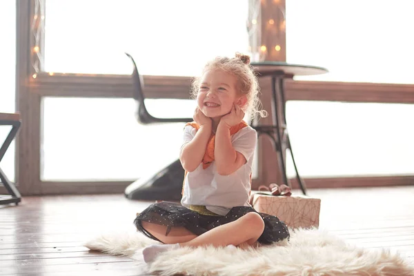 Niña feliz sentada en la alfombra en la sala de estar. — Foto de Stock
