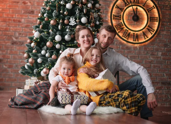 Dos hermanas y sus padres sentados cerca del árbol de Navidad — Foto de Stock