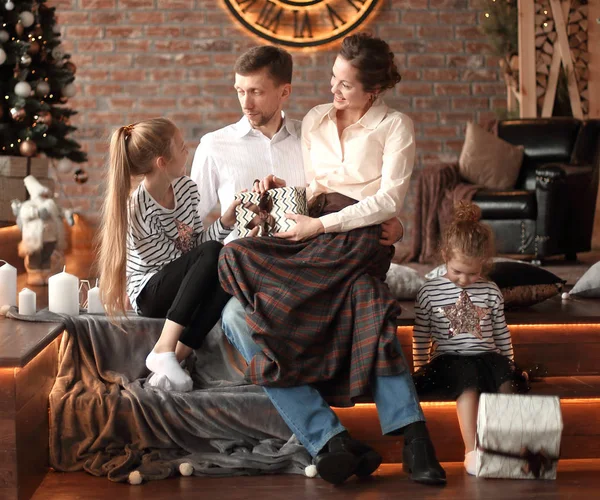 Padres con sus hijos pequeños sentados en la sala de estar decorada para Navidad — Foto de Stock