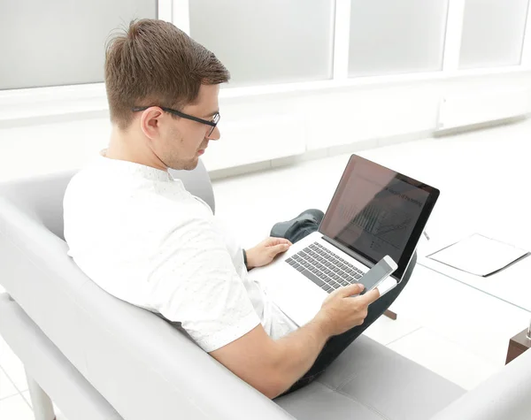 Businessman uses gadgets sitting in the office lobby . — Stock Photo, Image