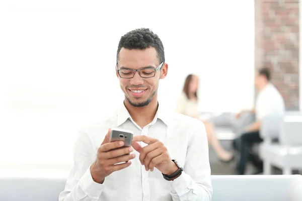 Sorrindo jovem lendo SMS em seu smartphone — Fotografia de Stock