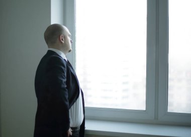 Ciddi bir işadamı ofisin penceresinden dışarı bakar.