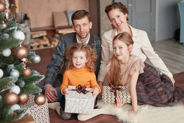 Familia feliz sentado cerca del árbol de Navidad en la noche de Navidad — Foto de Stock