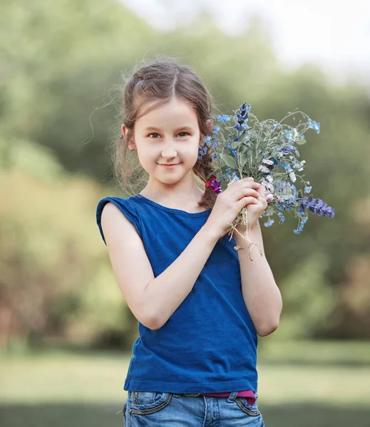 Petite fille avec un bouquet de fleurs sauvages. — Photo
