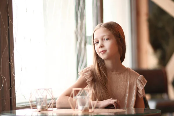 Aranyos lány ül egy asztalnál egy kávézóban — Stock Fotó