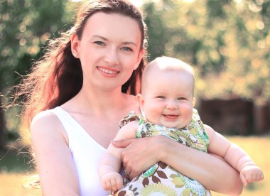 mutlu anne küçük bir kızı onun kollarında tutar.