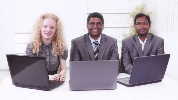 Empleados sentados frente a portátiles abiertos. aislado en blanco — Foto de Stock