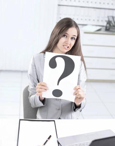 Upprörd affärskvinna som innehar ett frågetecken, sitter bakom en — Stockfoto