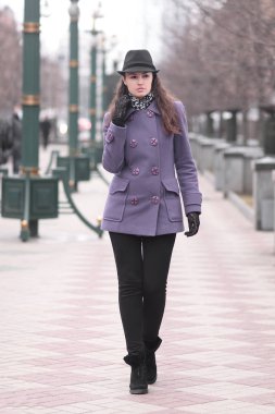 Şehir Bulvarı yürüyüş şapka ve sonbahar paltolu şık genç kadın