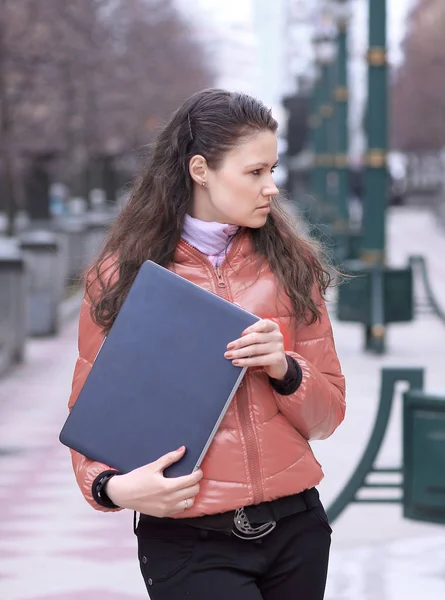 Young female student with laptop standing on city street — Stock Photo, Image