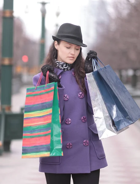 Jovem mulher de chapéu com sacos de compras multicoloridos — Fotografia de Stock
