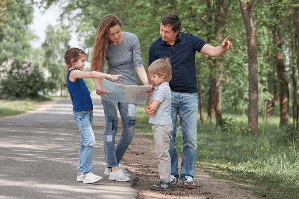 Familj med en vägkarta stående vid vägkanten. f — Stockfoto