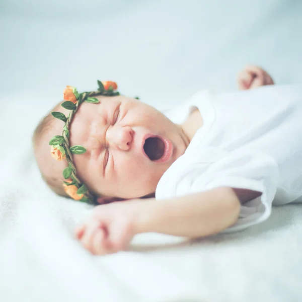 Pasgeboren baby in de kranslegging op het bed en gegaap — Stockfoto