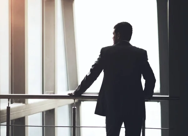 Empresario mirando por la ventana pensando en ideas de negocios — Foto de Stock