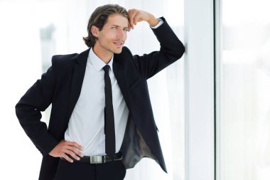 office penceresinde yakın duran gülümseyen iş adamı