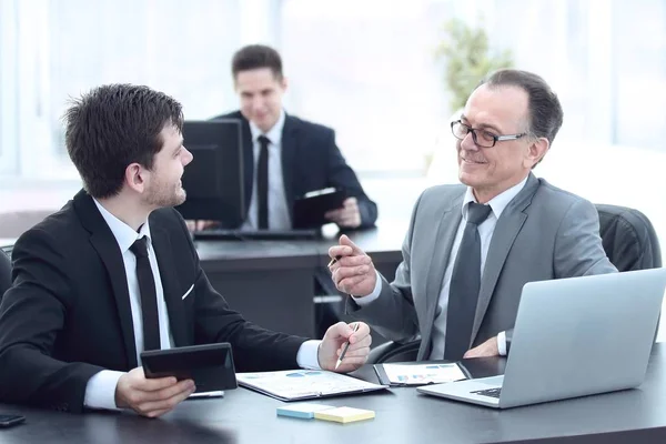 boss and employee discussing the document sitting at the Desk in the office.