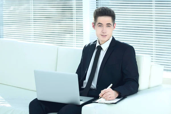 Впевнений бізнесмен працює на ноутбуці, сидячи в просторому — стокове фото