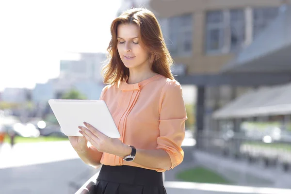 Mujer joven seria con tableta digital sobre fondo borroso de la ciudad — Foto de Stock