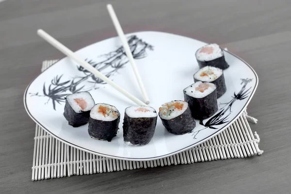 Close-up de sushi e pauzinhos em uma placa branca — Fotografia de Stock