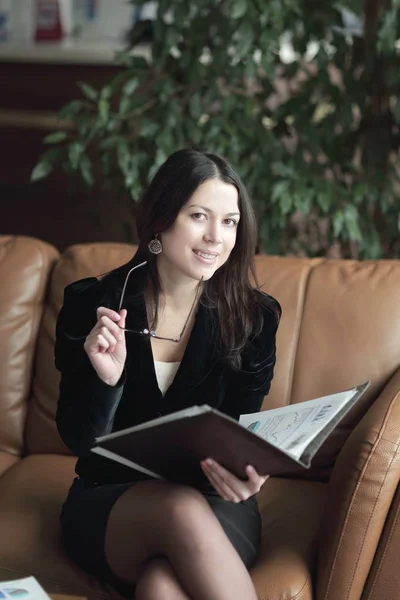 Close up.elegant mulher de negócios olhando através de documentos financeiros em um moderno centro de negócios — Fotografia de Stock