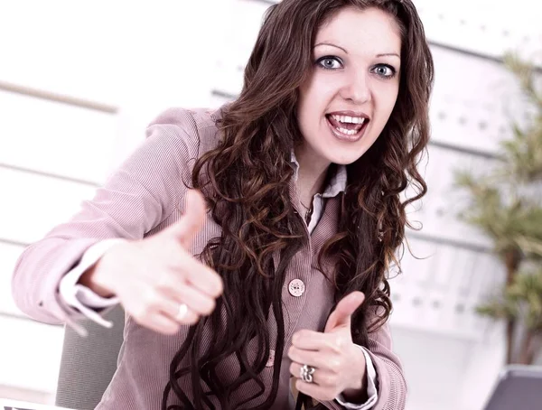 Confident business woman sitting at Desk and showing thumb up — Stock Photo, Image