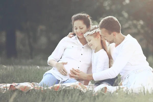 Pai feliz de uma filha e uma mãe grávida em um piquenique — Fotografia de Stock