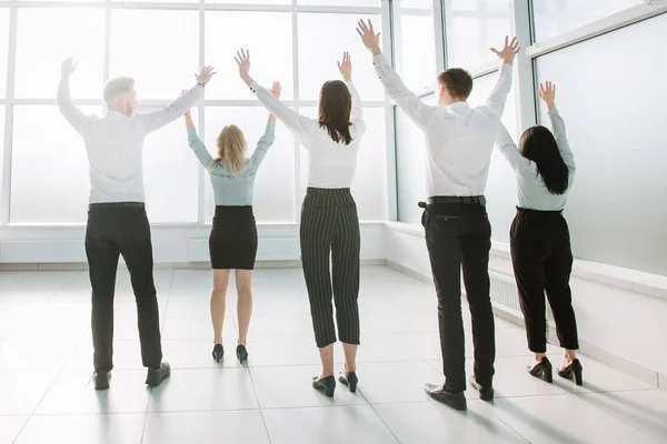 Posteriore view.happy business team in piedi in luminoso nuovo ufficio . — Foto Stock