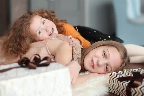 Dos hermosas hermanas tumbadas en el suelo en una acogedora sala de estar — Foto de Stock