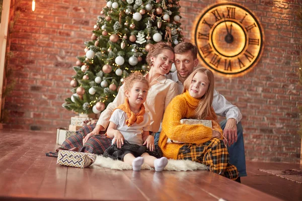 Familia feliz sentado cerca del árbol de Navidad en la acogedora sala de estar — Foto de Stock