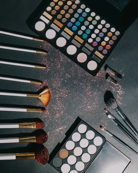 Pinceles de maquillaje y sombra de ojos sobre fondo negro . — Foto de Stock