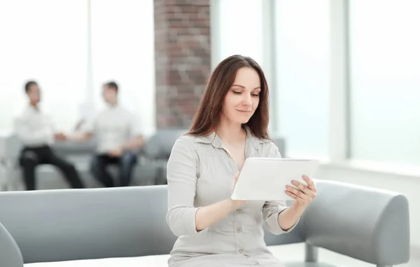 Деловая женщина с цифровым планшетом сидит на диване в офисном холле — стоковое фото