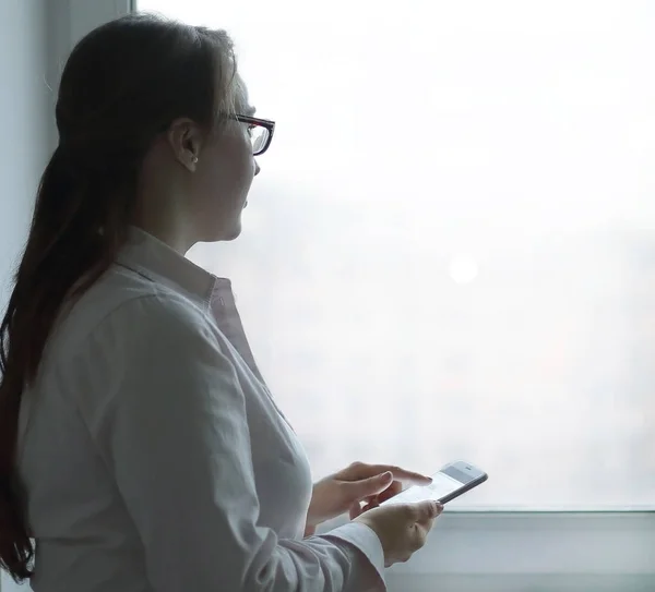 Iş kadını ile bir ofis pencere yanında dururken bir smartphone. — Stok fotoğraf