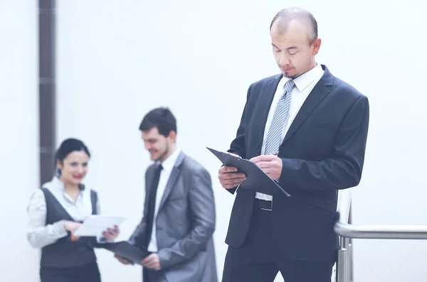 Hombre de negocios leyendo un documento de trabajo de pie en la oficina — Foto de Stock